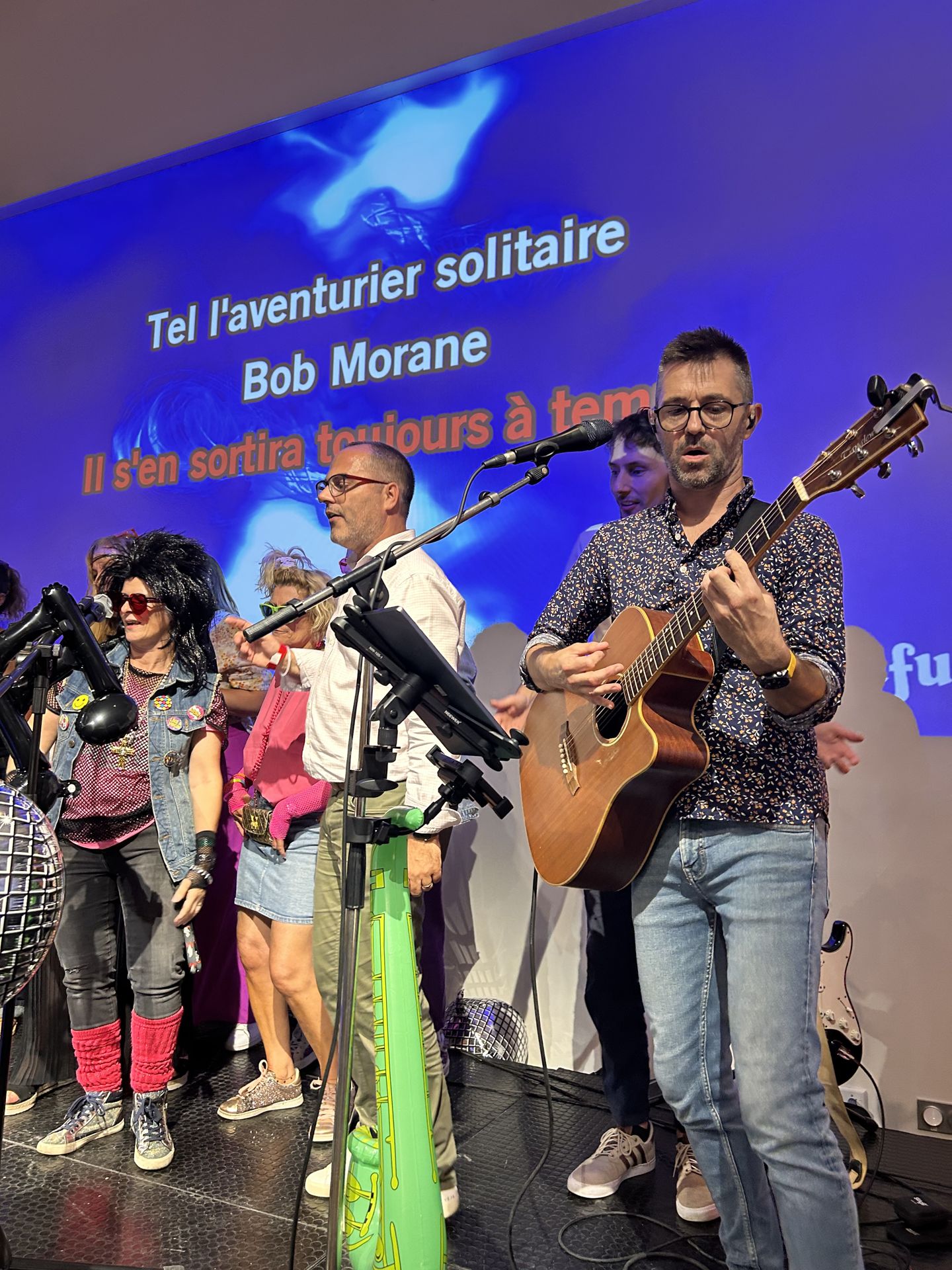 Le groupe live accompagne les chanteurs, paroles sur l'écran