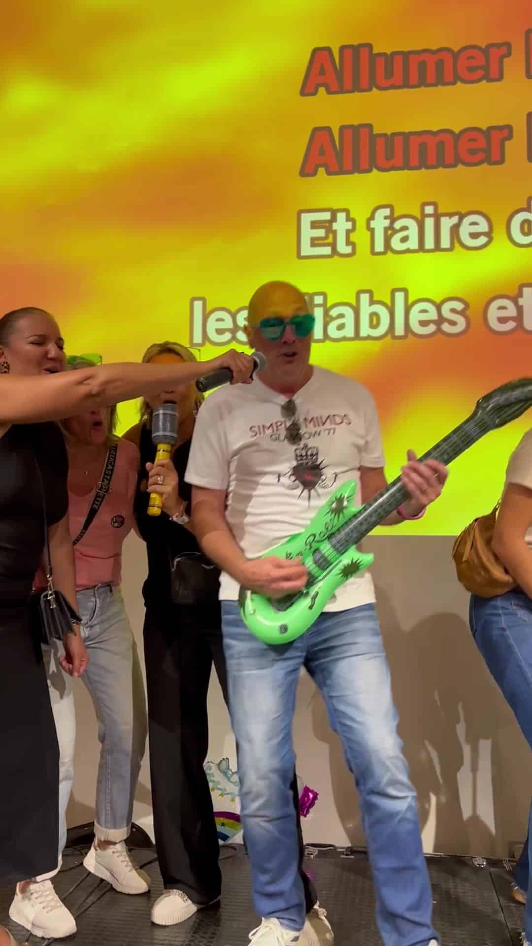 Un salarié chante avec une guitare gonflable, paroles à l'écran