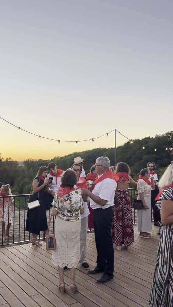 Invités en blanc et foulard rouge sur la terrasse du Domaine de Lassalle au coucher du soleil